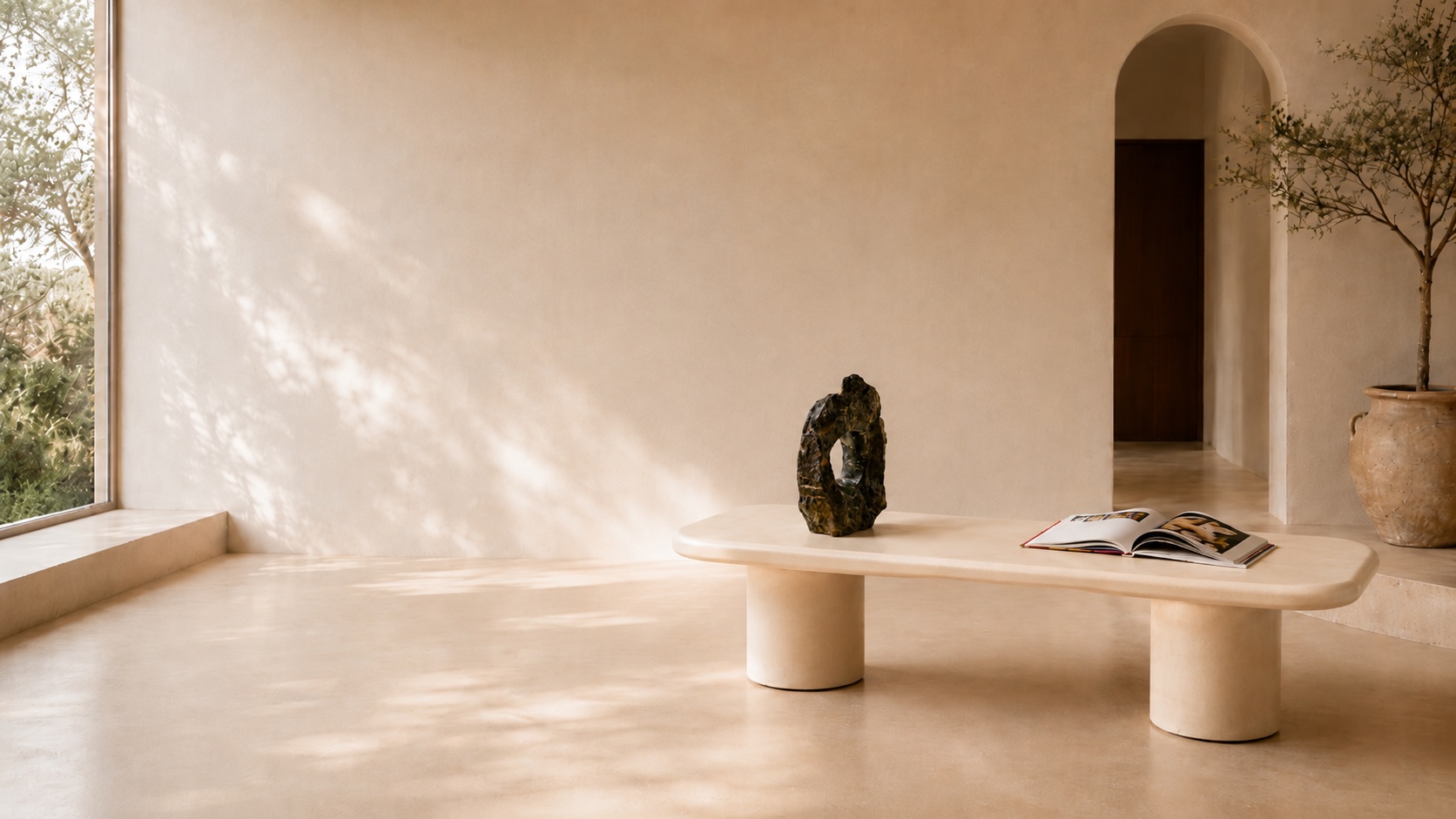 Table basse sur mesure en Mortex ivoire, sculpture en pierre noire et livre ouvert, dans une maison d'architecte baignée de lumière naturelle